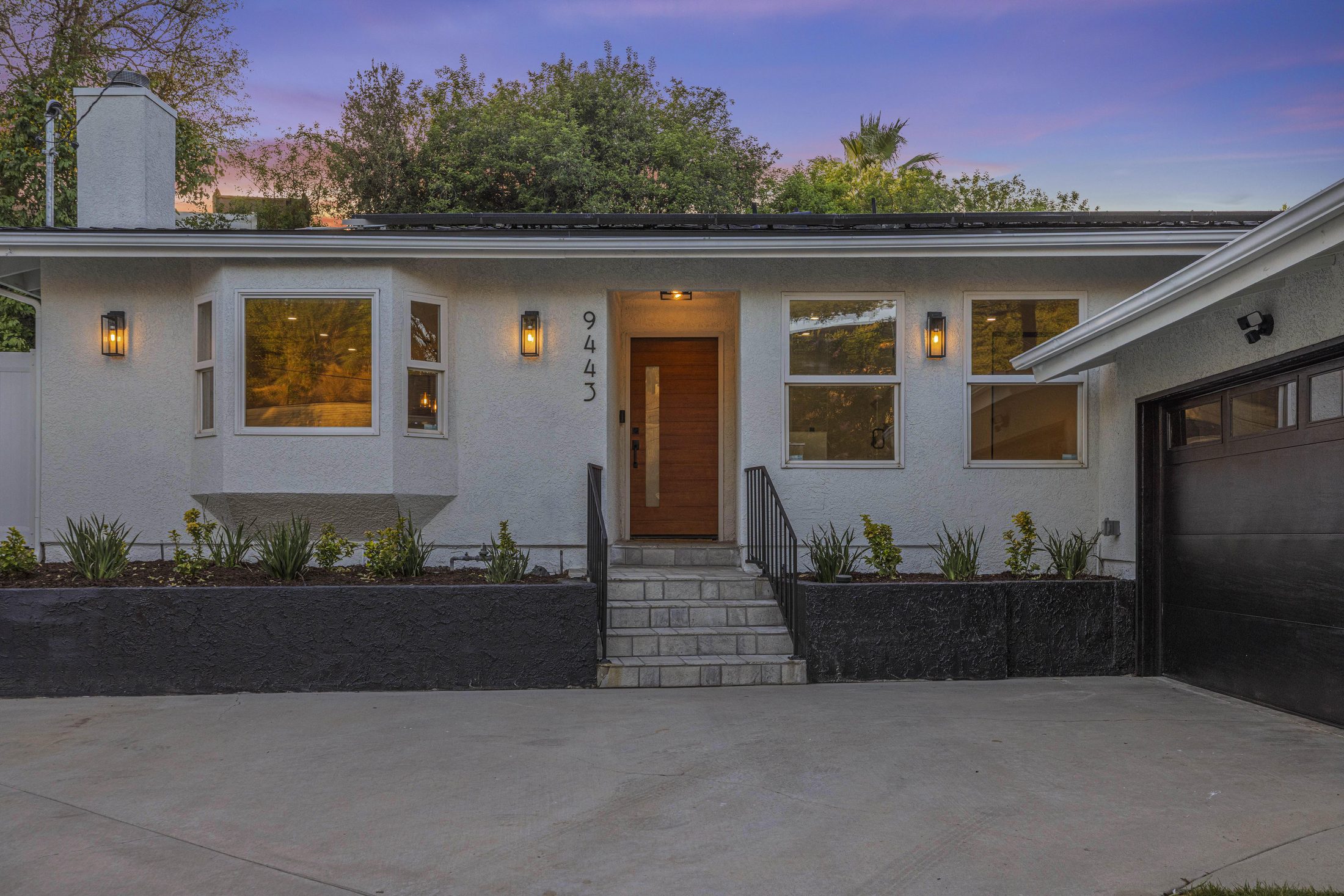 Front exterior of 9443 McLennan Ave at dusk with warm entry lighting